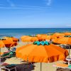 Spiaggia con lettini e ombrelloni arancioni.