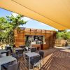 Terrazza con tavoli, sedie e bar. Ombrellone beige sopra.