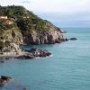 Scogliera con case e mare azzurro, piccola spiaggia rocciosa.