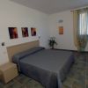 Una camera da letto con letto matrimoniale, piastrelle verdi e finestre con tende leggere.