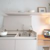 Cucina compatta con lavello, laptop e pentola bianca.