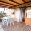 Veranda con tavolo bianco e sedie su pavimento in legno.