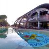 Edificio moderno con ampie vetrate, piscina con logo, e area pranzo esterna.