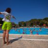 Persona guida un gruppo in piscina sotto un cielo blu.