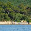 Spiaggia circondata da fitte colline boschive.