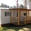 Casa mobile con veranda in legno tra alberi.