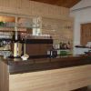 Un bancone bar in legno con bicchieri, bottiglie e una macchina da caffè.